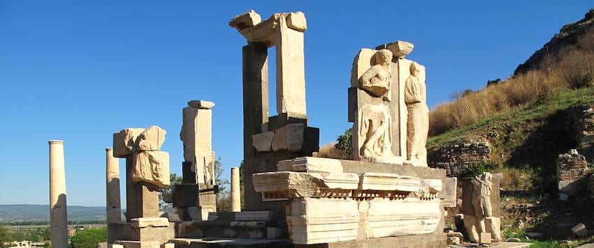 Monumento de Memmio en Éfeso, con sus figuras talladas en relieve sobre bloques de mármol y la ladera seca al fondo